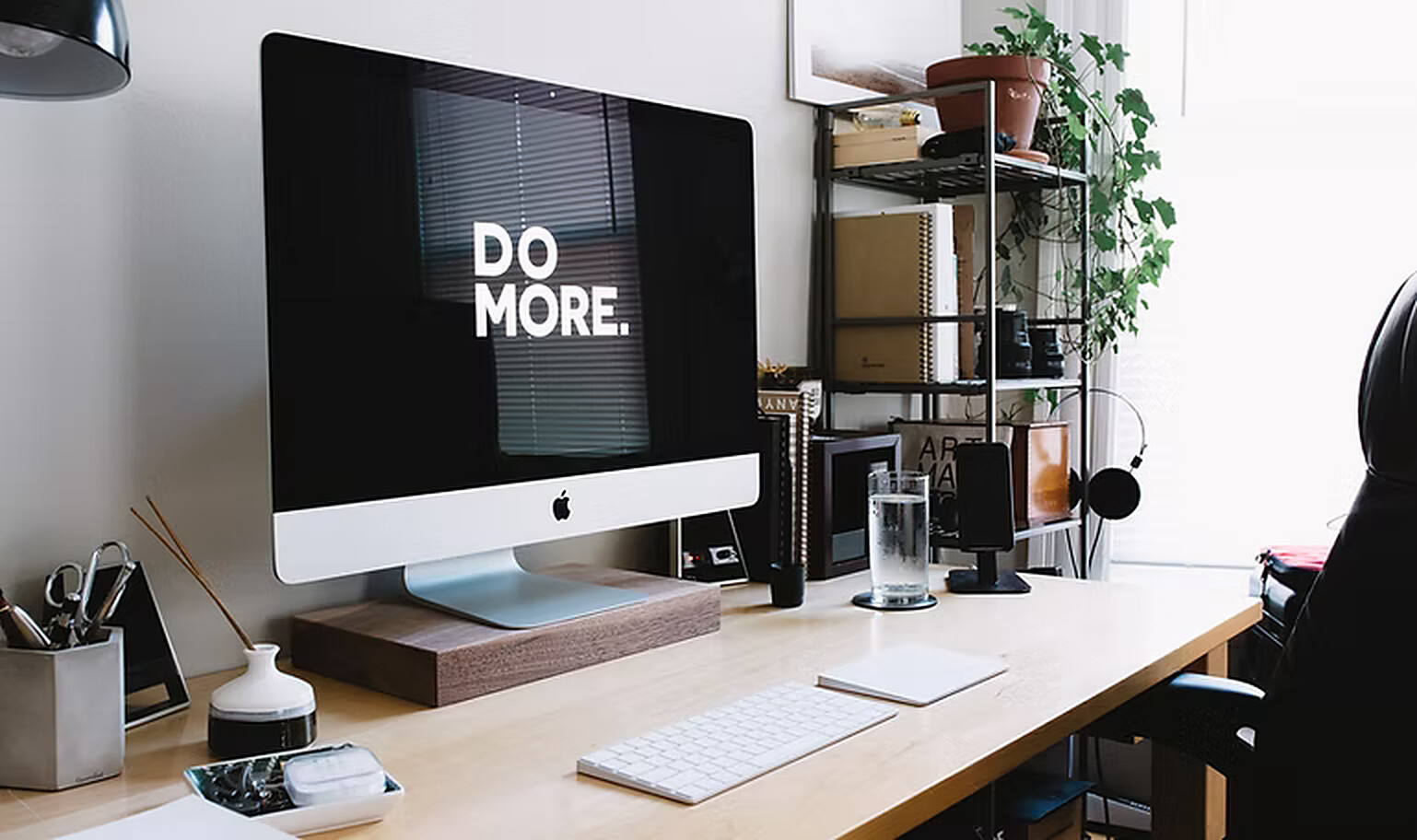 A clean desk workspace with an iMac displaying the words DO MORE